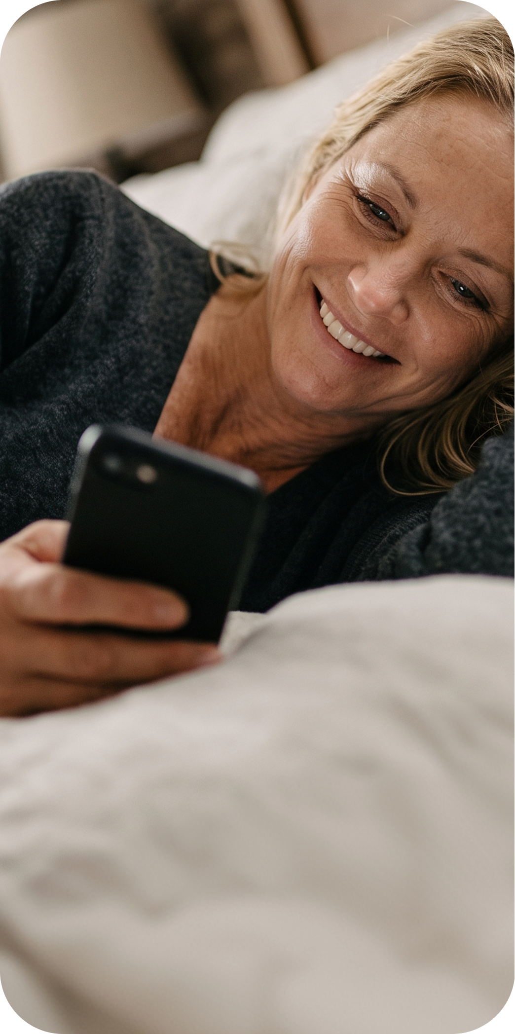 Mulher sorrindo usa celular em cama