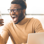 Homem negro com óculos e expressão de surpresa olhando para um celular.