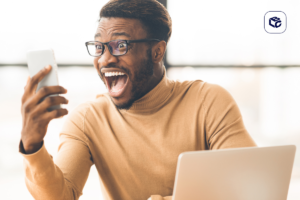 Homem negro com óculos e expressão de surpresa olhando para um celular.